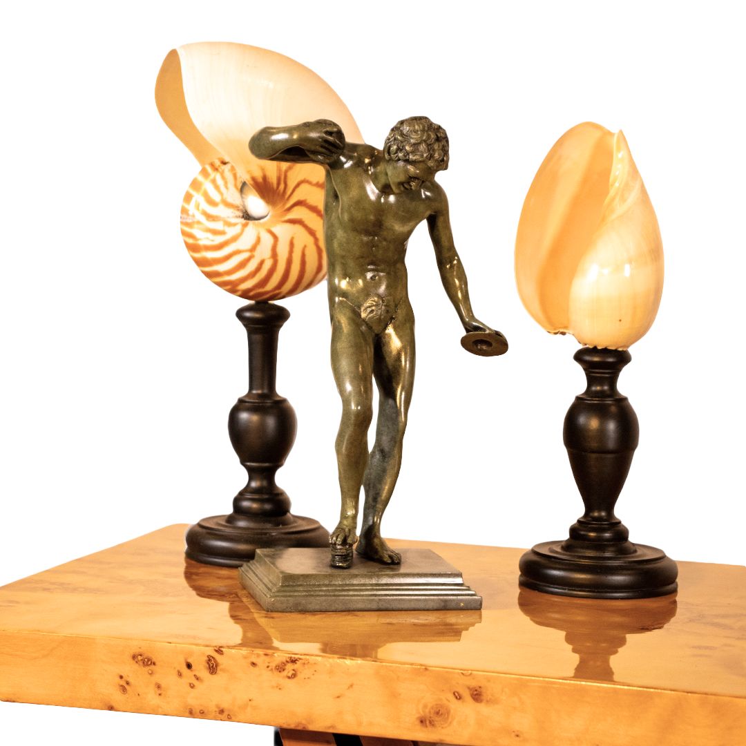Art Deco console table with burl walnut top featuring bronze male sculpture and nautilus shell lamps, elegant decorative vignette