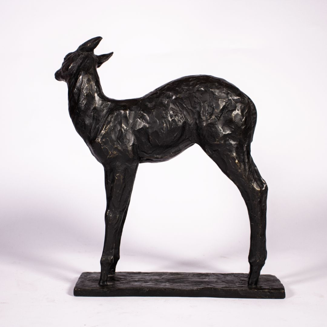 Left side view of bronze sculpture of a fawn deer with dark patina