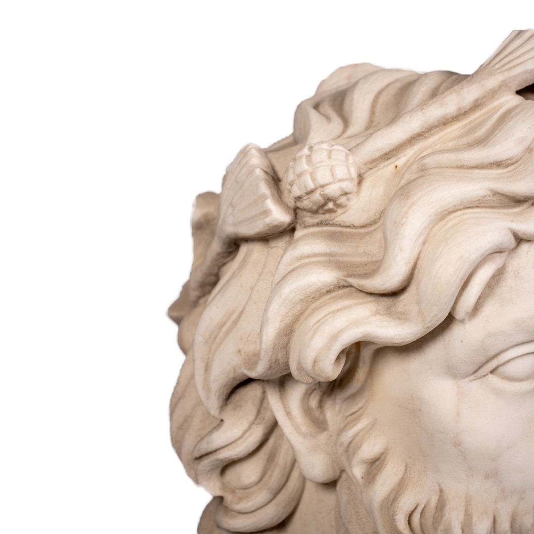 Carved white marble bust head with flowing hair and grape cluster decoration on black marble base