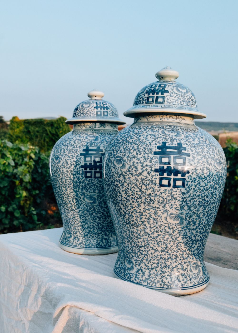 Chinese porcelain blue and white jars displayed on a table in a chateau vineyard near Reims with Taittinger champagne bottles in the background