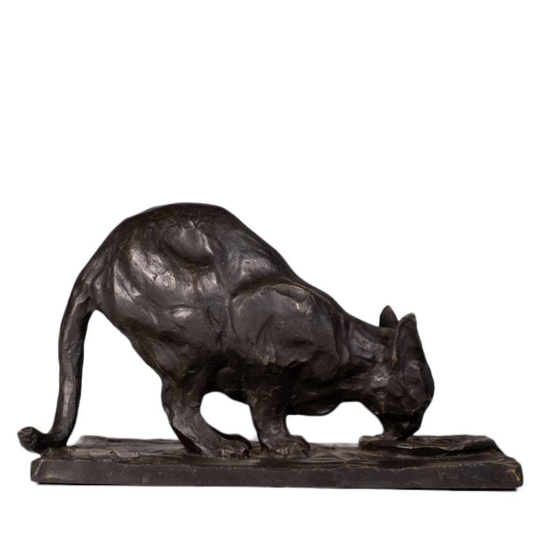 Gato bebiendo de bronce visto de perfil derecho, cola baja sobre el borde de la base, pátina marrón oscura